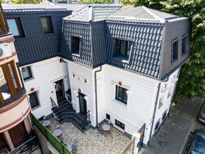 Un edificio de varios pisos con un patio interior, una escalera que sube a los pisos superiores y un pequeño espacio al aire libre con mesas y sillas.