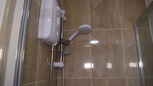 Een douche met een handdouche en een bedieningspaneel aan de muur.