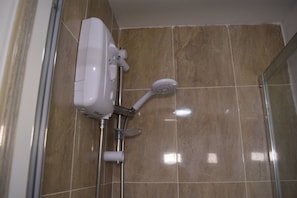 A shower with a handheld showerhead and a wall-mounted control unit.