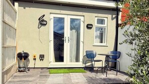 A residential property with a patio, a barbecue grill, and a small seating area with two chairs.