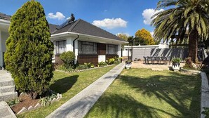 Una casa residenziale con vialetto lastricato, prato e area patio con mobili da esterno.