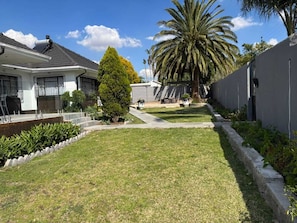 A residential area with a lawn, a palm tree, and a house with a chimney.