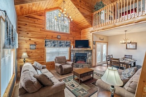 A cozy cabin interior with a fireplace, wooden walls, a dining area, and a balcony. - Pigeon Forge Hideaway (Pigeon Forge)