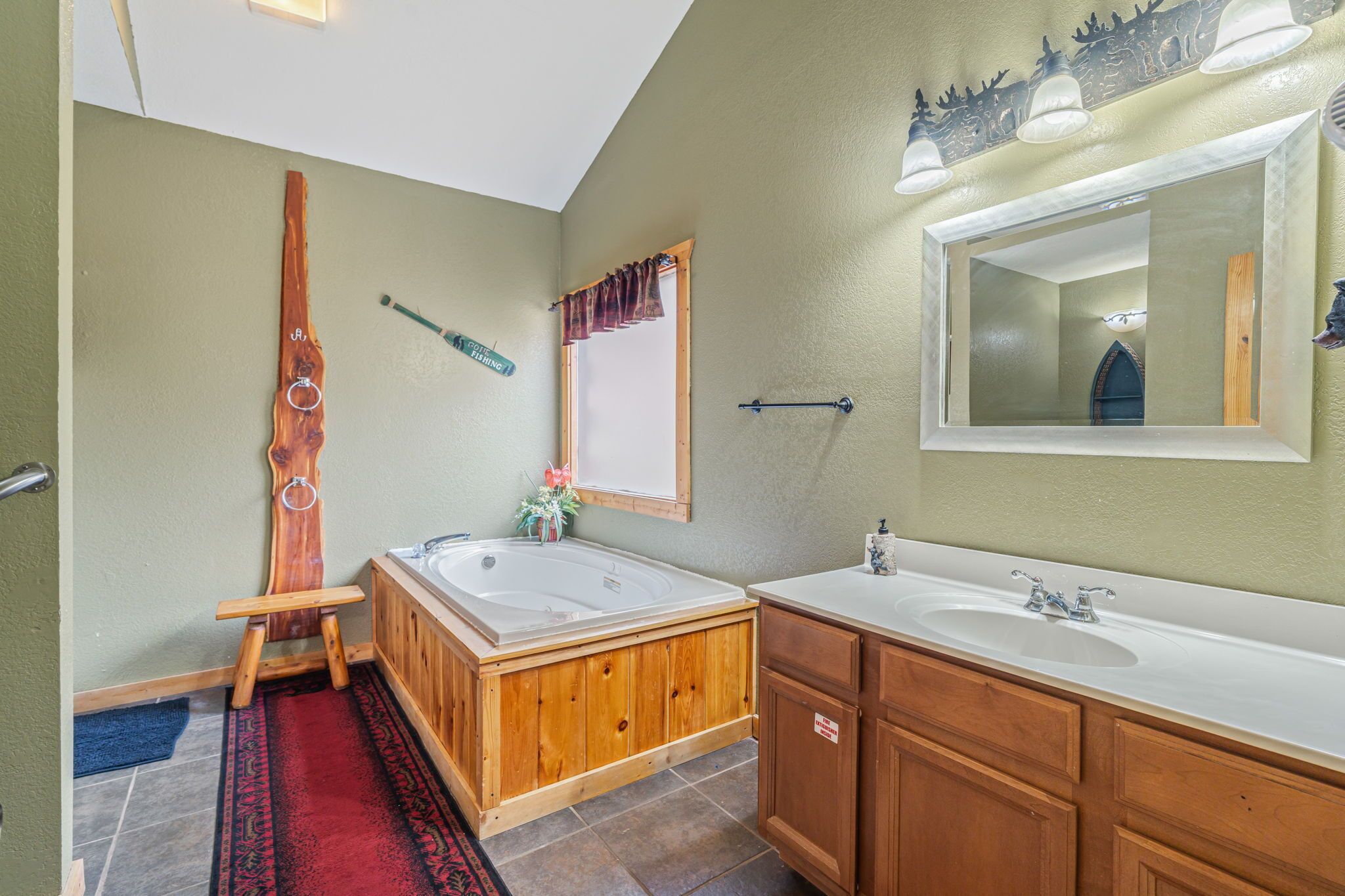 A bathroom with two sinks, wooden cabinets, a large mirror, and a wooden bathtub.