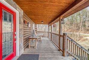 A wooden porch with a red door, a bench, and a table. - Pigeon Forge Hideaway (Pigeon Forge)