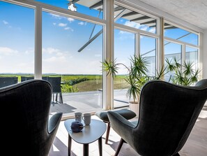 A modern room with large windows, a table with a ball of yarn, and two chairs. - "Jorkin" - 150m from the sea by Interhome (Ebeltoft)