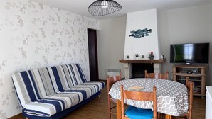 Ein Wohnzimmer mit einer Couch, einem Esstisch mit Stühlen, einem Kamin und einem Fernseher.