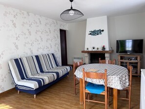 Ein Wohnzimmer mit einer Couch, einem Esstisch mit Stühlen, einem Kamin und einem Fernseher.