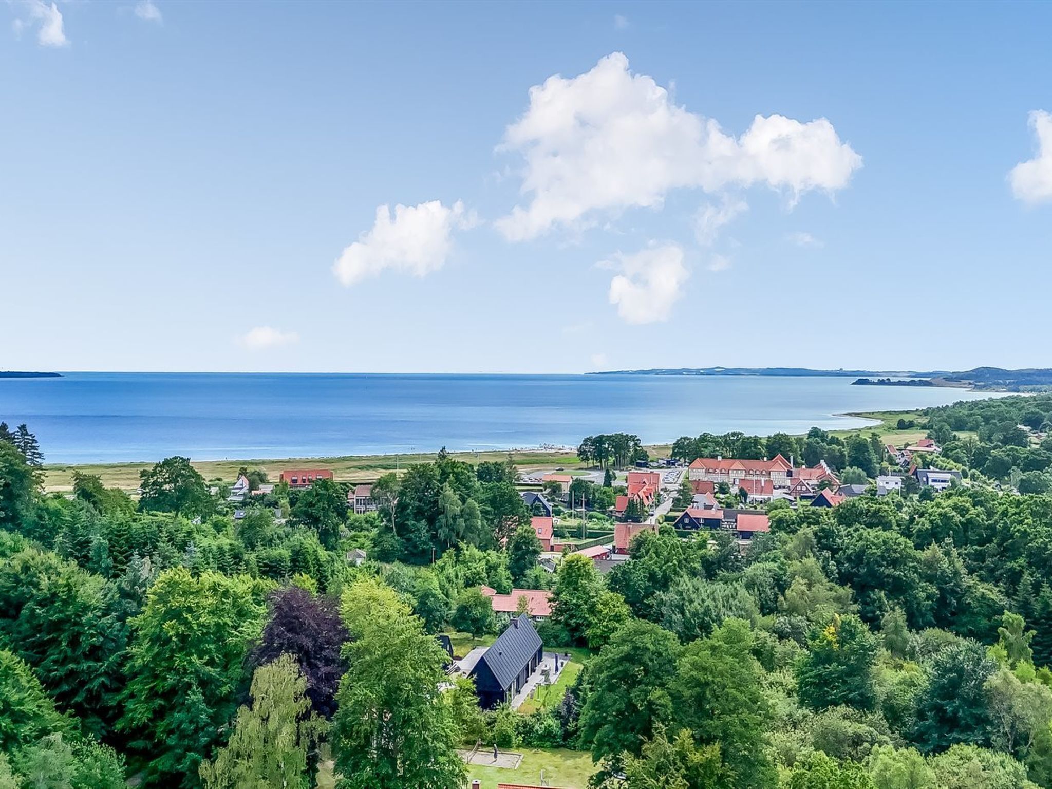 En kystby med huse, klar himmel og havudsigt.