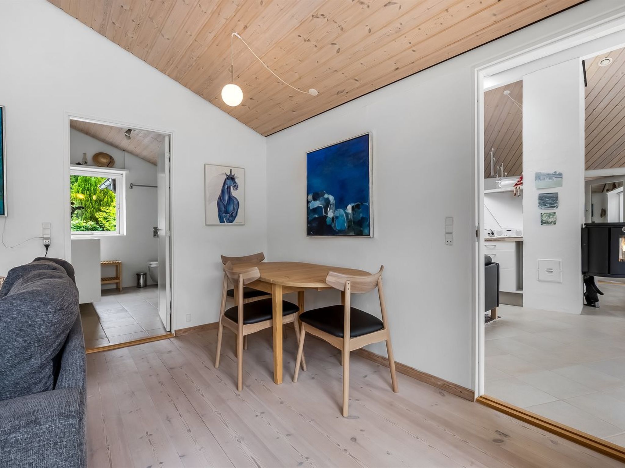 Et moderne interiør med spiseplads, sofa og billedkunst på væggene.