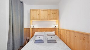 A bedroom with a wooden headboard, two bedside tables, and a bed with white bedding. - Apartment "Le Soleil des Alpages" with Mountain View (Slopes) and Balcony (La Plagne-Tarentaise)