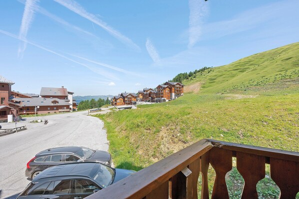 A hotel with multiple wooden buildings, a parking area, and a grassy hillside.