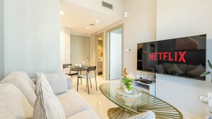 Moderni olohuone, jossa on sohva, sohvapöytä ja seinälle asennettu televisio, jonka näytöllä näkyy Netflixin logo.