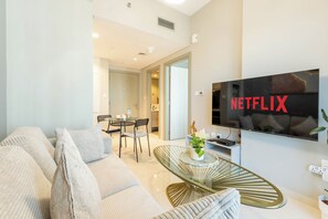 Ein modernes Wohnzimmer mit Sofa, Couchtisch und einem an der Wand montierten Fernseher, der das Netflix-Logo zeigt.