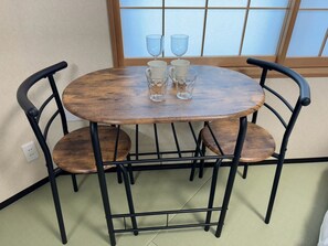 A round wooden table with four chairs, two glass cups, and a small white object on the table. - Newly Opened Right Next to JR Kamata Station: YU'S HOUSE 2 (大田区)