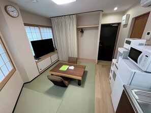 A compact living space with a dining table, a TV, a microwave, and a small kitchenette. - Newly Opened Right Next to JR Kamata Station: YU'S HOUSE 2 (大田区)