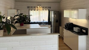 Een moderne keuken met witte kasten, een centraal eiland, roestvrijstalen apparatuur en uitzicht op de eetruimte.