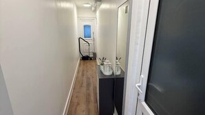 A narrow hallway with a wooden floor, a door with a frosted glass panel, and a small table with a vase and candle. - Cosy skylight Modern Studio + Free Private Parking (Greater London)
