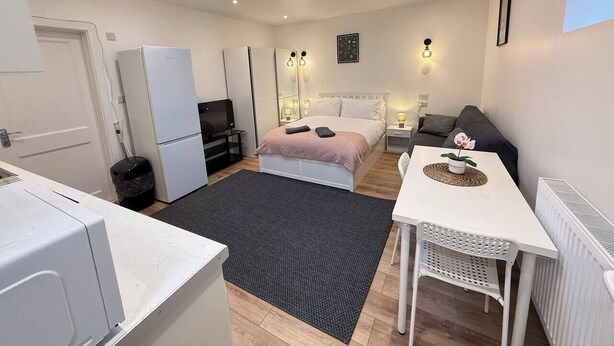A compact room with a bed, a small table, a sofa, a kitchenette, and a skylight. - Cosy skylight Modern Studio + Free Private Parking (Greater London)