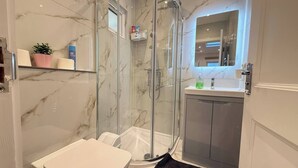 A modern bathroom with a glass-enclosed shower, a toilet, a sink, and a mirror. - Cosy skylight Modern Studio + Free Private Parking (Greater London)