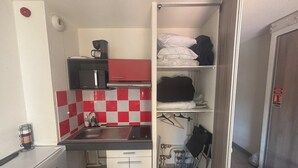 Une petite cuisine équipée d’un four à micro-ondes, d’un évier et d’étagères de rangement.