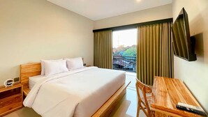 A hotel room with a bed, a desk, a chair, a TV, and a window with curtains. - Cozzy Ketewel Beach Villa (gianyar)