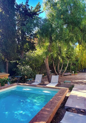 A swimming pool surrounded by trees and a wooden deck.