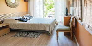 Un dormitorio con cama, una silla, una mesita, un espejo y una ventana con persianas.