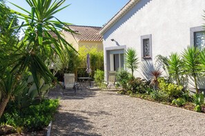A courtyard with a gravel path, a table with chairs, and various plants.