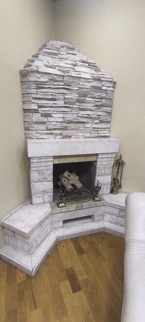 A stone fireplace with a mantel, a decorative metal piece, and a small statue on the mantel. - Cozy 2-bedroom apartment in fantastic Bakı with AC (Bakı)