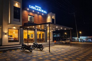Un hotel moderno con entrada cubierta, asientos al aire libre y motocicletas estacionadas.