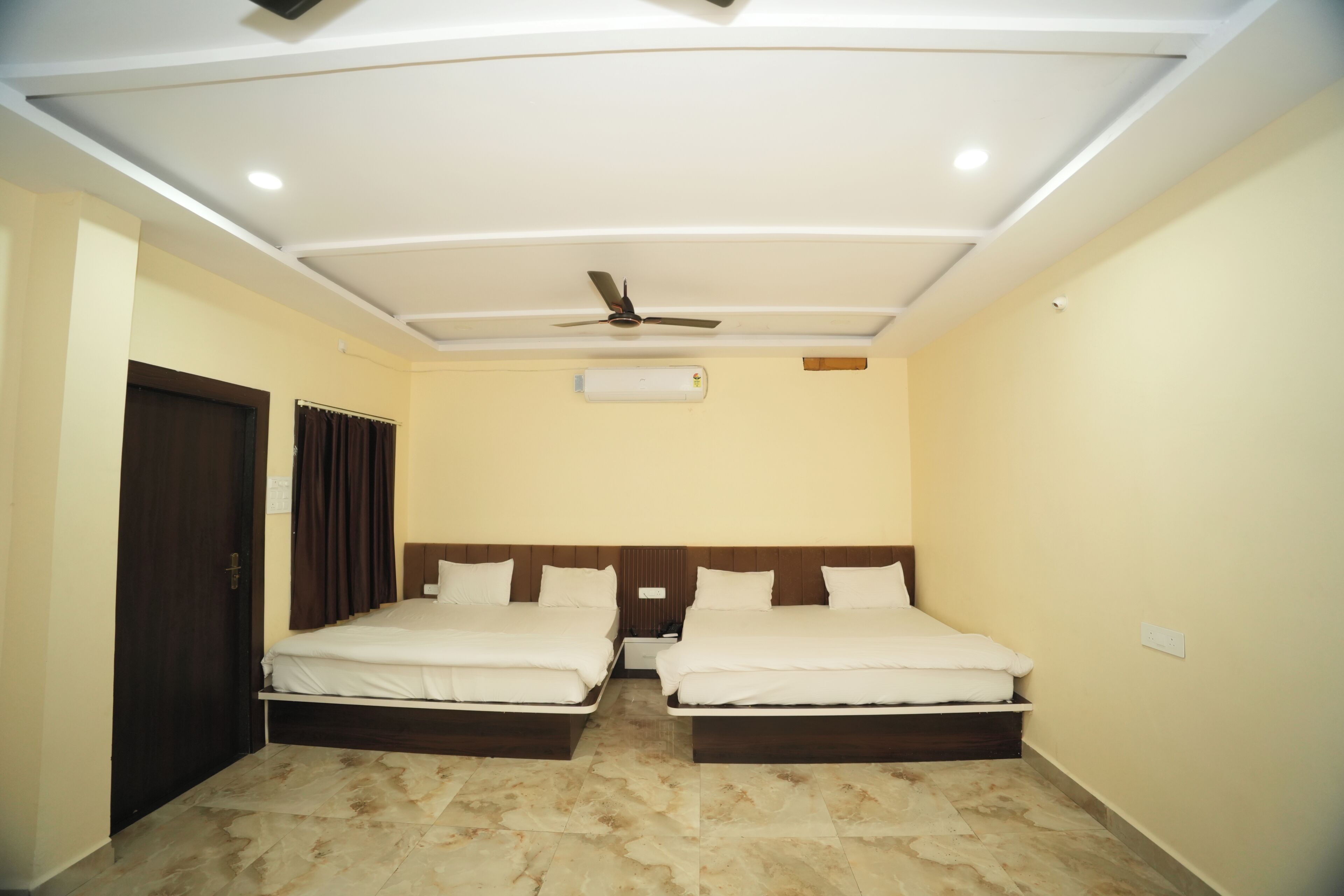 A hotel room with two beds, a ceiling fan, recessed lighting, and a tiled floor.