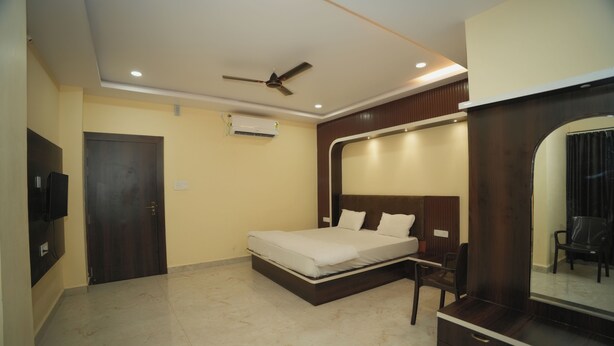 A bedroom with a bed, a ceiling fan, a wardrobe, and a mirror. - Hotel Leelanchal (Sehore)