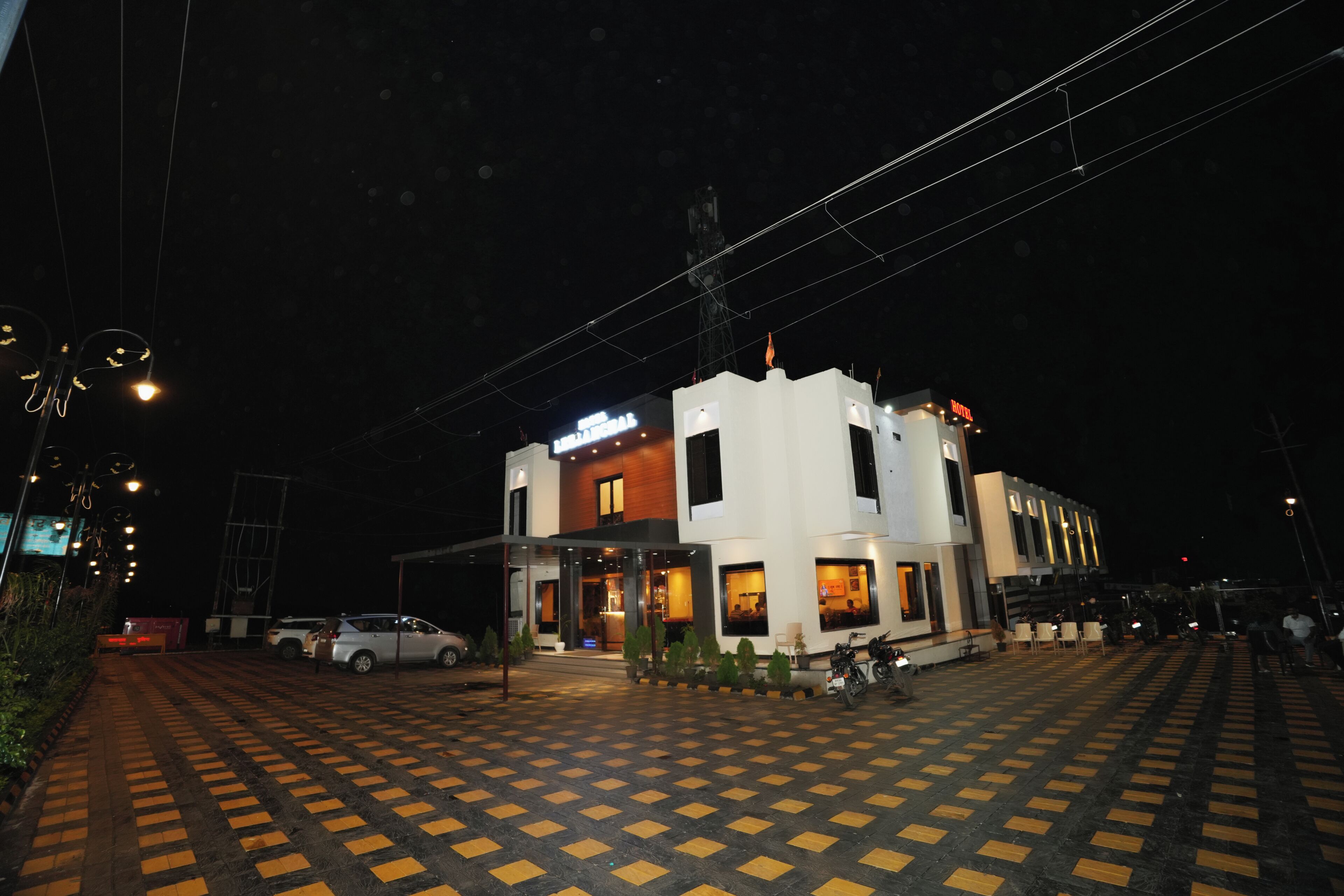 A hotel with a checkered floor, a car parked outside, and a building with a sign.