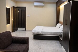 Un dormitorio con cama, una silla, un armario y un equipo de aire acondicionado.