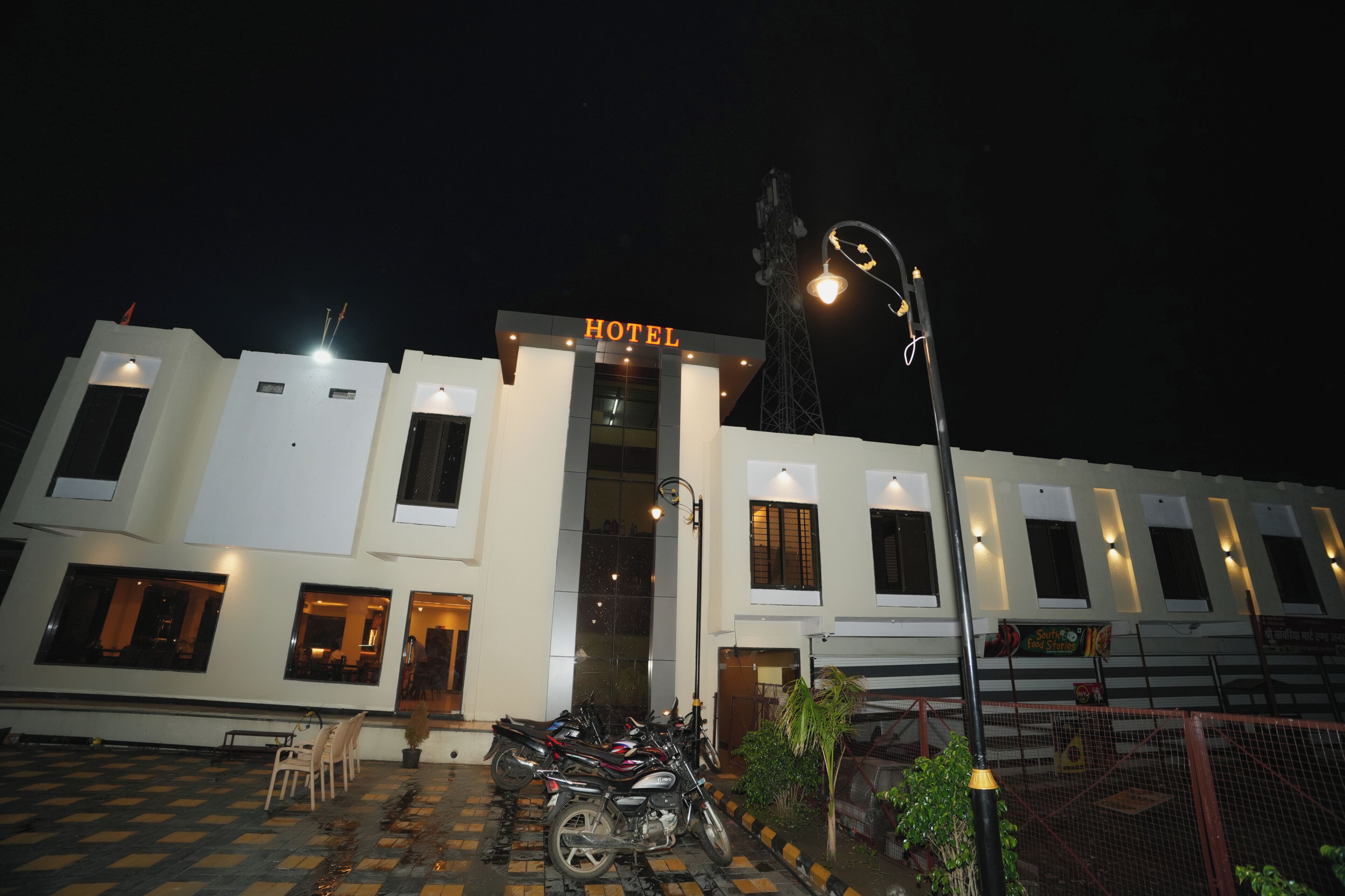 A hotel with a sign, a parking area with motorcycles, and a gated entrance.