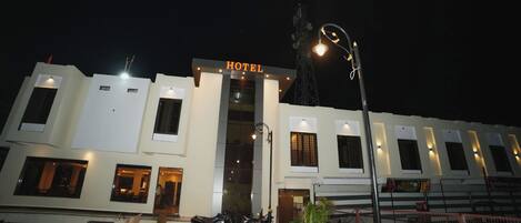 A hotel with a sign, a parking area with motorcycles, and a gated entrance.