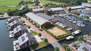 A marina with boats docked, a large building with a flat roof, and a river. - Gorgeous home in Uitgeest with house sea view (Uitgeest)