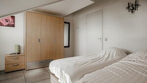 A bedroom with a bed, a wardrobe, a bedside table, and a wall-mounted light fixture. - Gorgeous home in Uitgeest with house sea view (Uitgeest)
