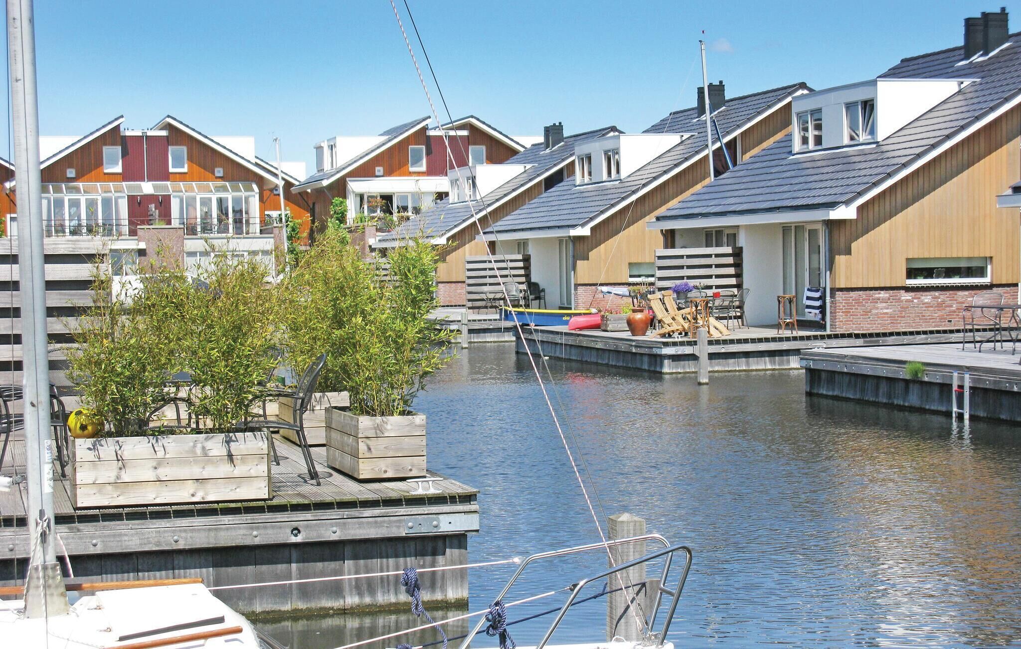 A canal-side property with a dock, wooden deck, and a row of houses with sloped roofs.
