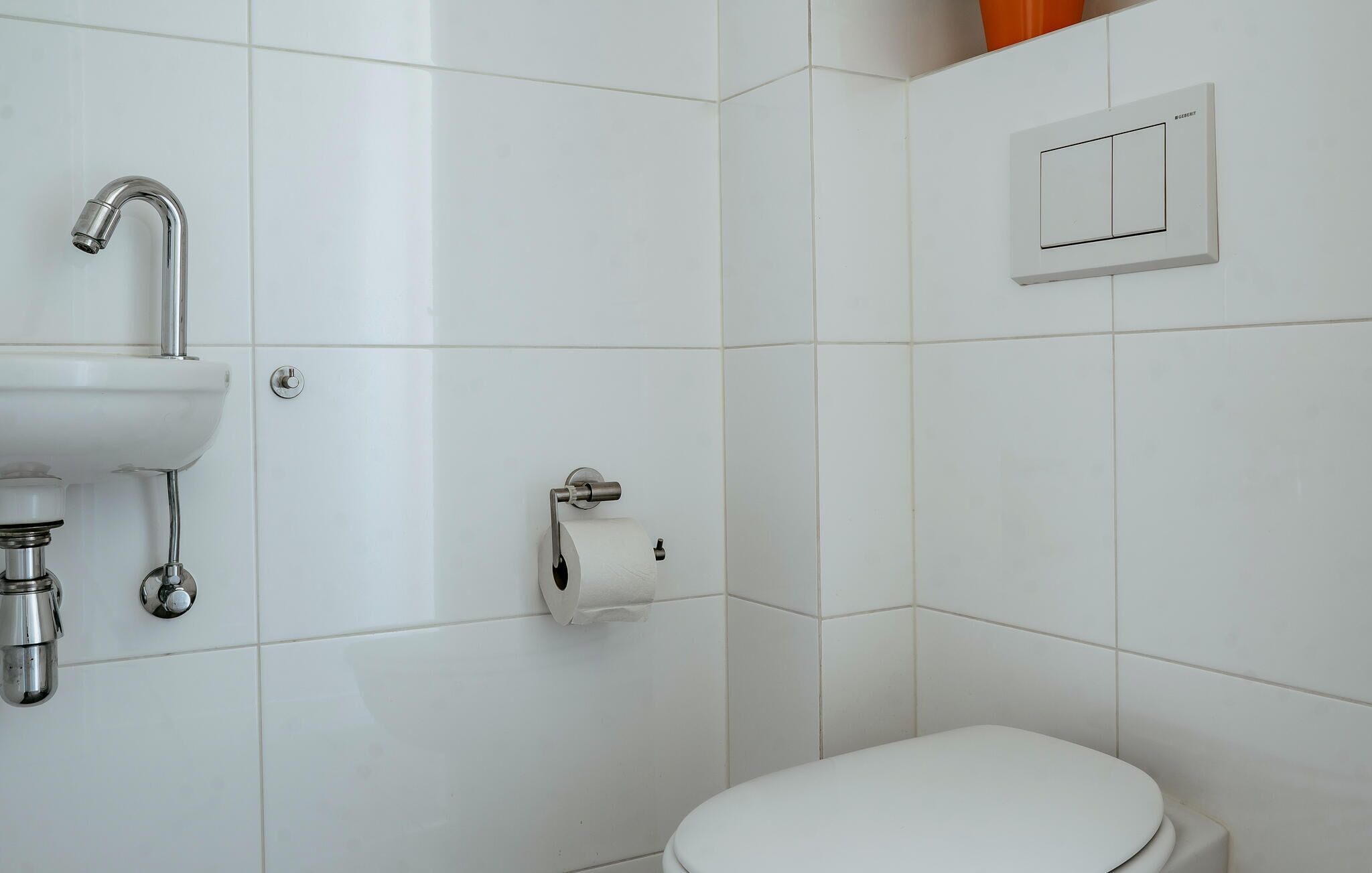 Baño con lavamanos, inodoro y un interruptor de luz en la pared.