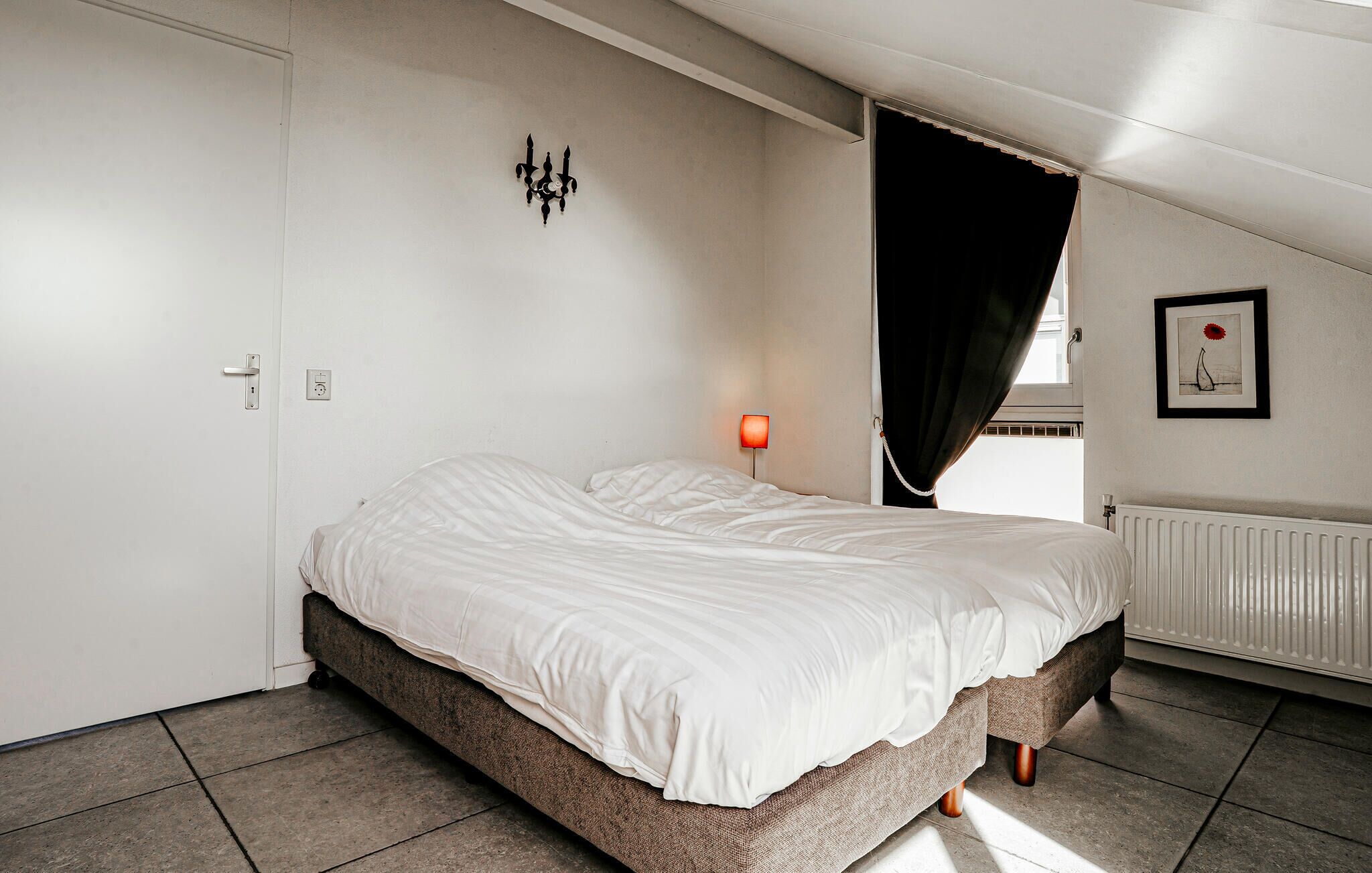 Ein Schlafzimmer mit einem Bett, einer Wandleuchte, einer Heizung und einer Tür.