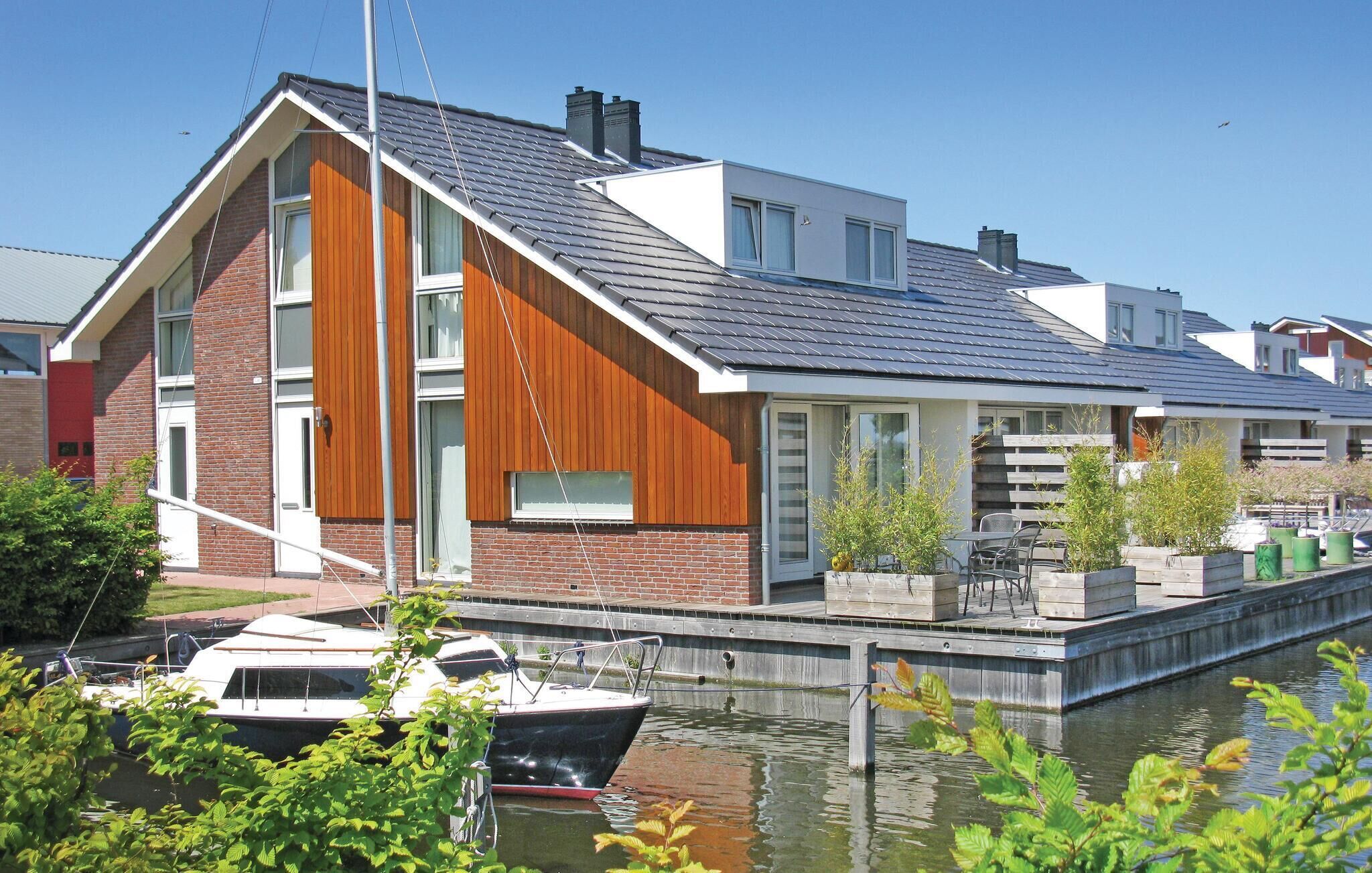 A modern house with a sloped roof, large windows, and a dock with a boat.