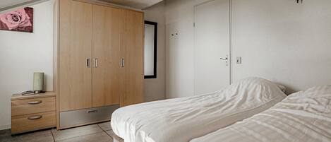 Ein Schlafzimmer mit Bett, Schrank, Nachttisch und einer Wandleuchte.