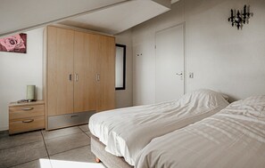 Ein Schlafzimmer mit Bett, Schrank, Nachttisch und einer Wandleuchte.