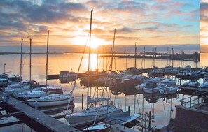 A marina with boats docked, a sunset in the background, and a distant pier. - Cozy home in Uitgeest with house sea view (Uitgeest)