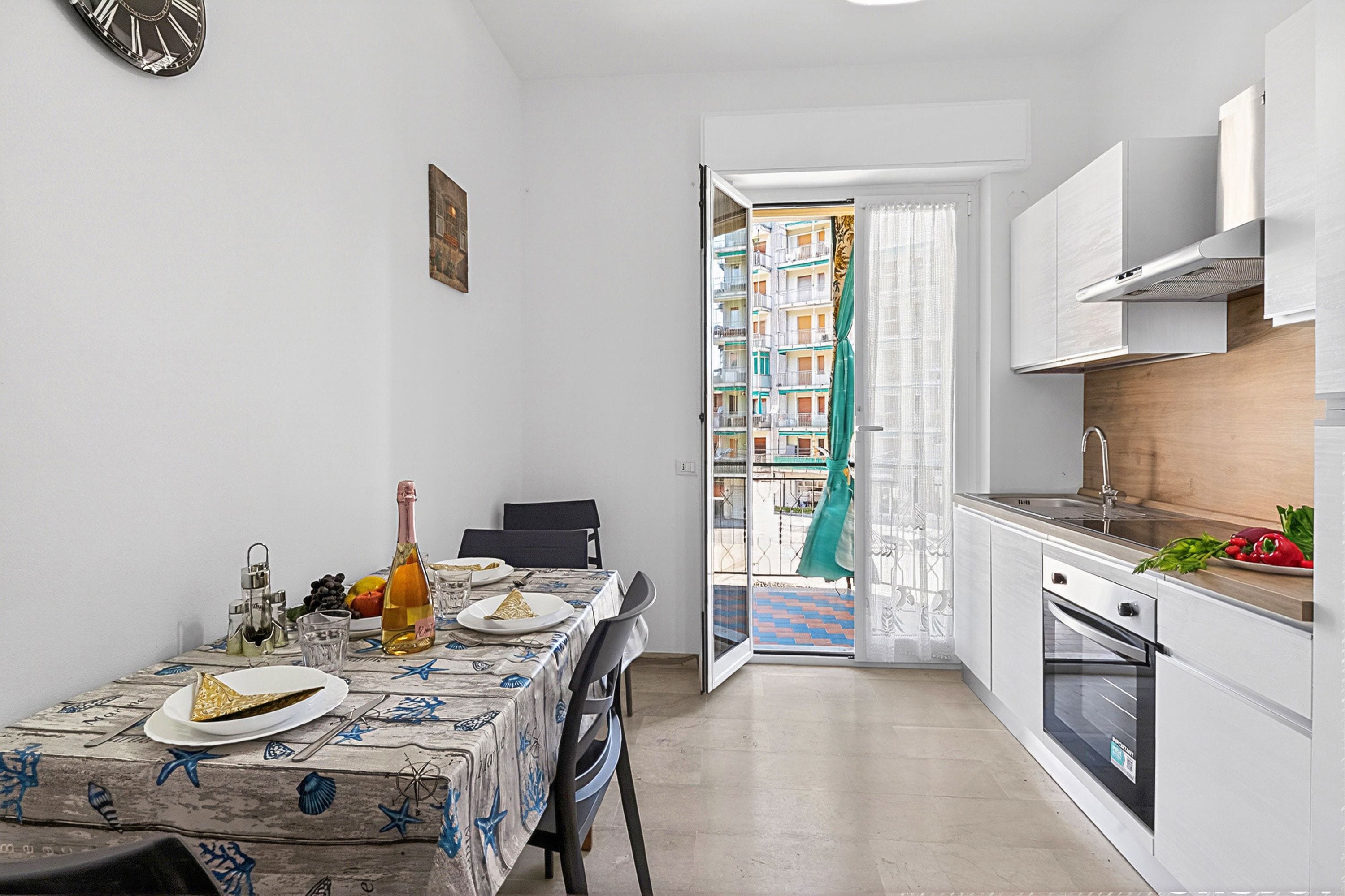 Cocina compacta con una mesa de comedor para dos personas, horno empotrado y vistas a un balcón con barandilla.