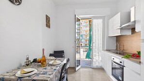 Una cucina compatta con un tavolo da pranzo per due persone, forno a incasso e vista su un balcone con ringhiera.
