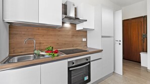 Una cucina moderna con forno integrato, lavello in acciaio inossidabile e mobili in legno.