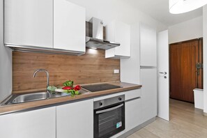 A modern kitchen with a built-in oven, a stainless steel sink, and wooden cabinetry. - House Carletta 200m From The Sea (Borghetto Santo Spirito)
